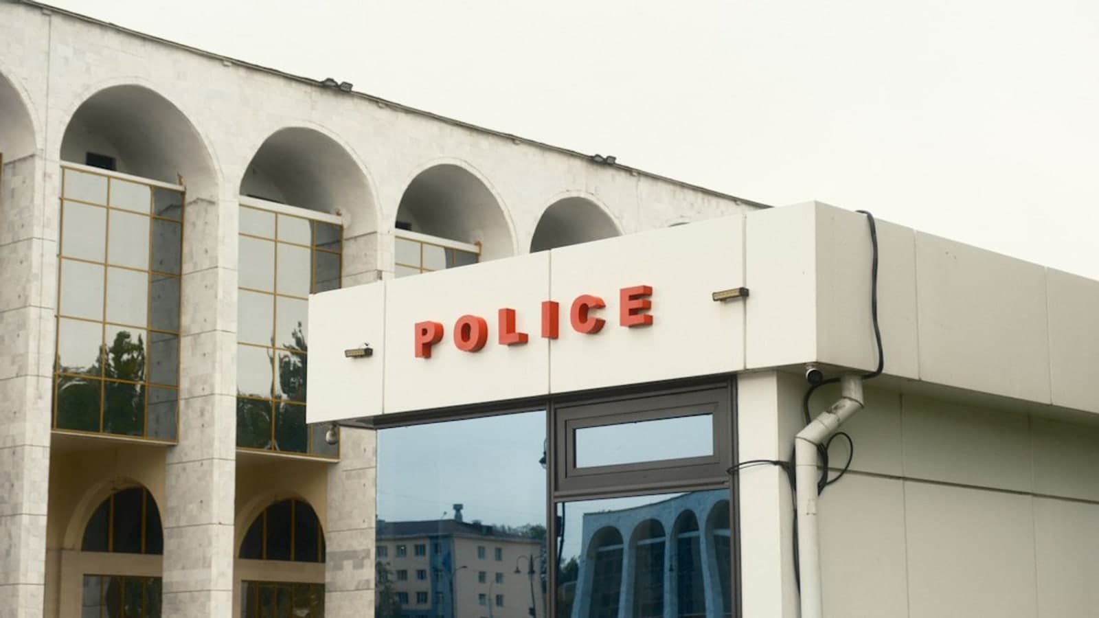A modern police station with arched architectural features and reflective glass windows under an overcast sky — illustrative photograph
