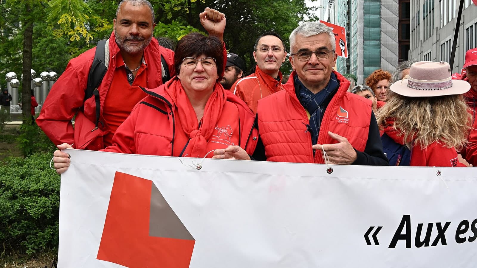 A group of protesters in red jackets hold a banner during an outdoor demonstration — illustrative photograph