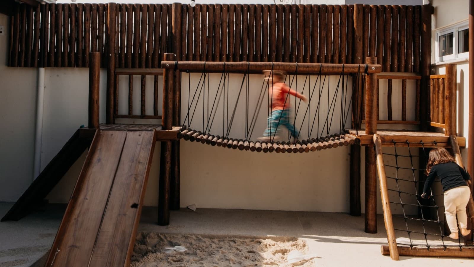 Kids enjoying a wooden playground with slides and ropes. Perfect for outdoor activities and fun — illustrative photograph