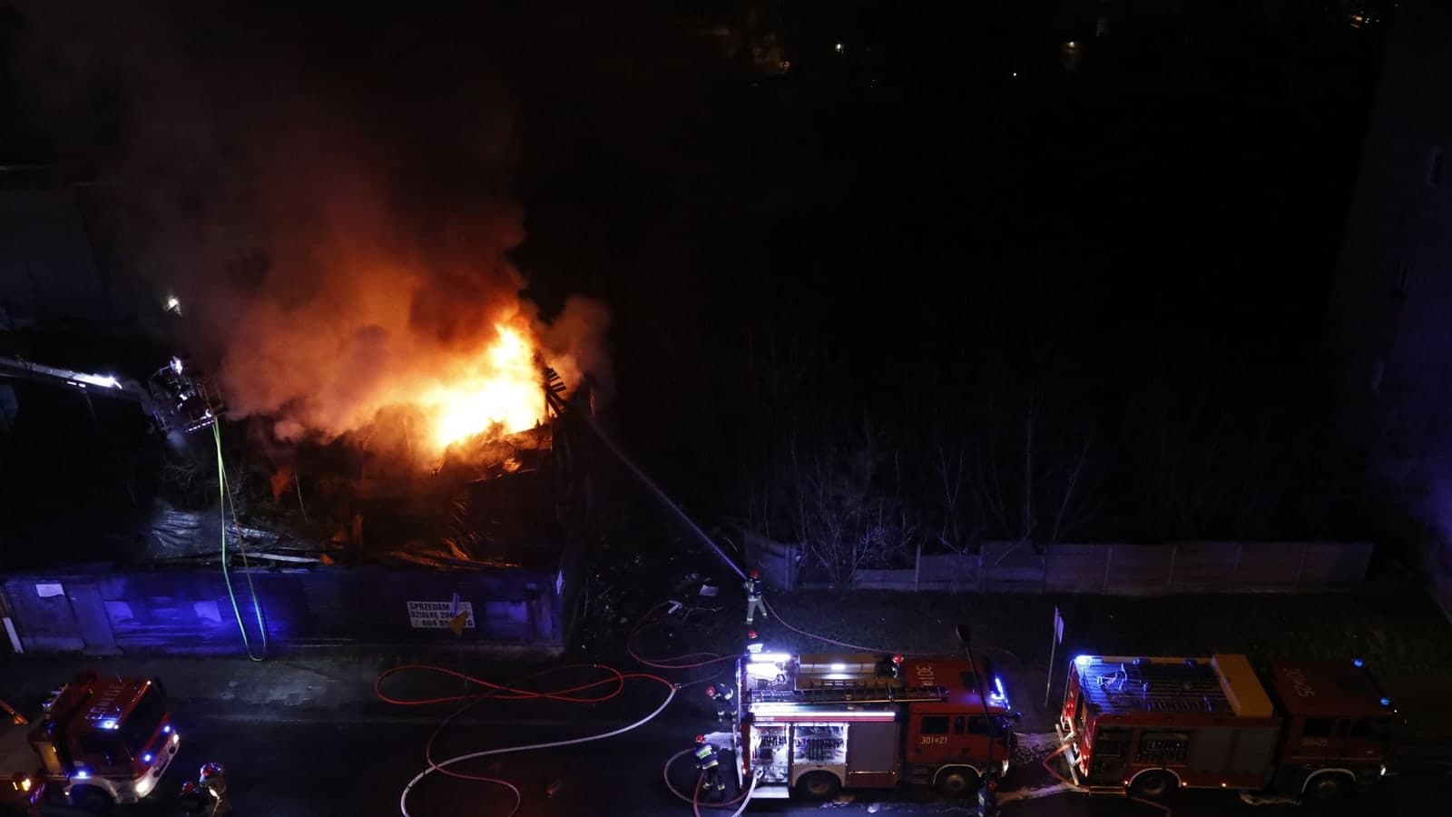 A dramatic nighttime scene of firefighters extinguishing a building fire — illustrative photograph